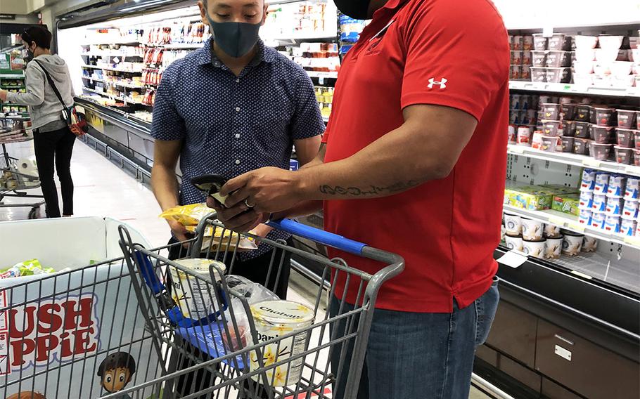 Fidelis Rides volunteers Gunnery Sgt. Michael Diggs and Lance Cpl. Luis Flores Gonzalez check a shopping list from someone who used the group's new U-Shop service at the Camp Foster commissary, Wednesday, April 29, 2020.