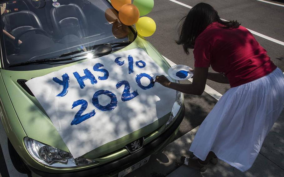 Yokota High School guidance counselor Rene Kelley paints a poster on her car before driving with students in a decision day parade at Yokota Air Base, Japan, Friday, May 1, 2020.