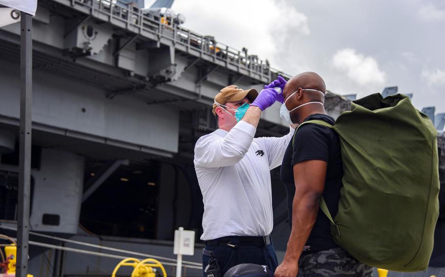 A sailor assigned to the USS Theodore Roosevelt prepares to board the aircraft carrier at Naval Base Guam, Friday, May 1, 2020. Those who have tested negative for the coronavirus, are asymptomatic and have completed their off-ship quarantine or isolation are allowed aboard the ship.