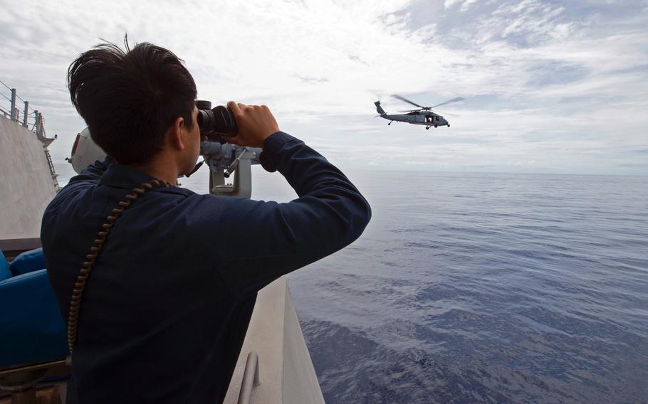 Petty Officer 3rd Class Adolfo Rodriguez of the USS Gabrielle Giffords stands watch as an MH-60S Sea Hawk takes off from the littoral combat ship's flight deck in the South China Sea, April 27, 2020.