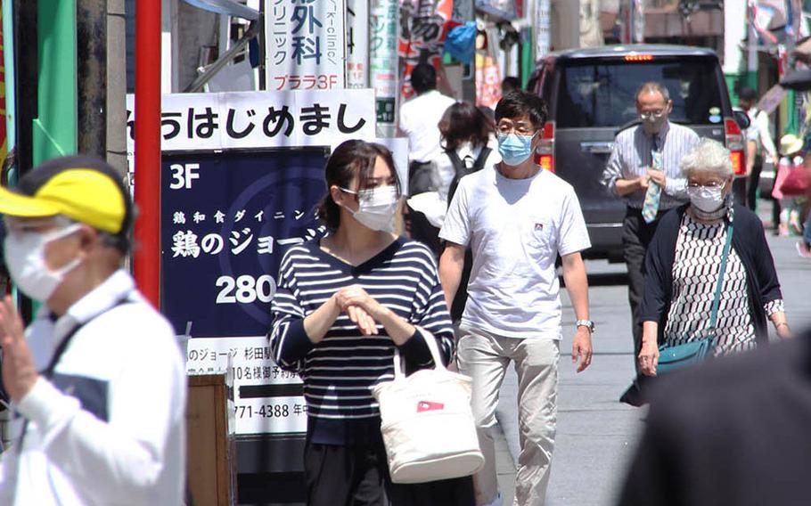 Pedestrians don face masks while out and about in Yokohama, Japan, Monday, May 11, 2020.