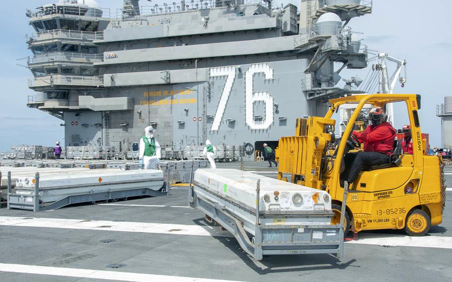 Sailors move and sanitize cargo on the flight deck of the aircraft carrier USS Ronald Reagan somewhere off the coast of Japan, Saturday, May 9, 2020.