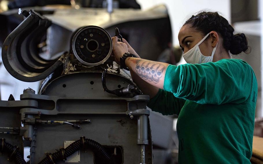 A sailor works on an MH-60R Sea Hawk aboard the aircraft carrier USS Ronald Reagan in the Philippine Sea, Monday, May 11, 2020.