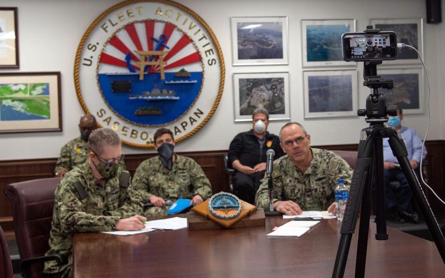 Sasebo Naval Base commander Capt. Brad Stallings, in front of microphone, uses Facebook Live to speak to sailors during the coronavirus pandemic, April 23, 2020.