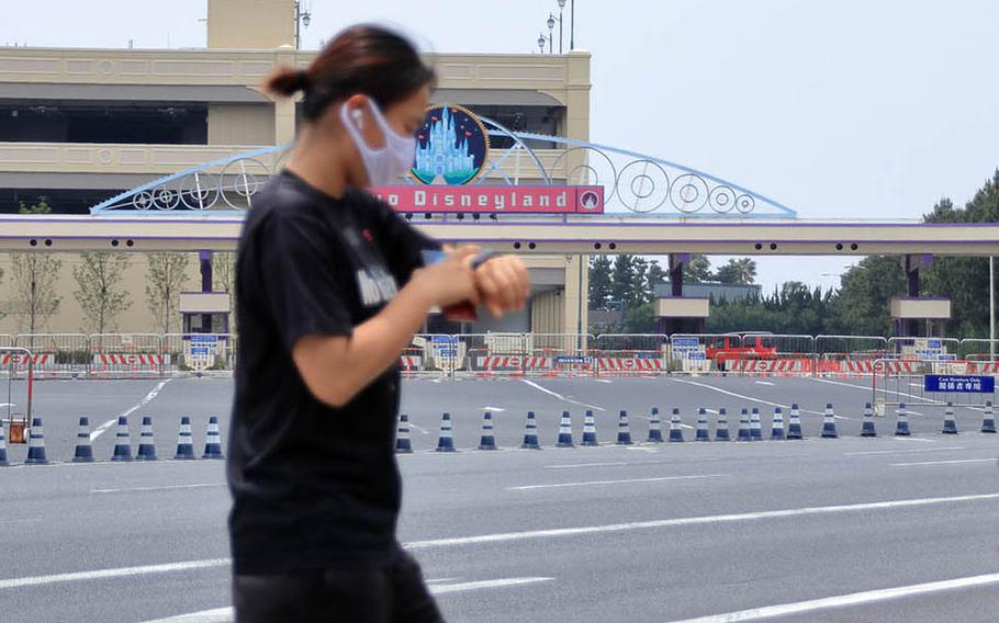 A jogger passes the shuttered entrance to Tokyo Disneyland in Urayasu, Japan, Tuesday, May 12, 2020.