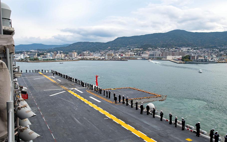 Sailors man the rails as the amphibious assault ship USS America arrives at Sasebo, Japan, Dec. 6, 2019.