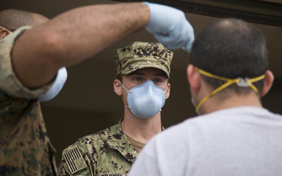 Hospital corpsmen from the 3rd Medical Battalion at Camp Foster, Okinawa, check a sailor assigned to the USS Theodore Roosevelt at Naval Base Guam, May 7, 2020.