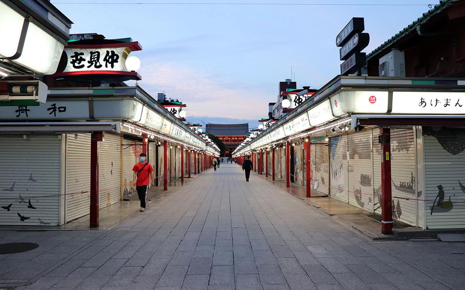 A few people stroll along the shuttered shops of Nakamise, a popular shopping street near Sensoji in Asakusa, Tokyo, Monday, May 25, 2020.