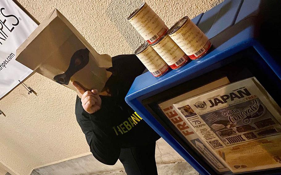 A Beefaroni Bandits member poses with cans of Beefaroni left outside the Stars and Stripes office at Yokota Air Base, Japan, Monday, June 1, 2020.