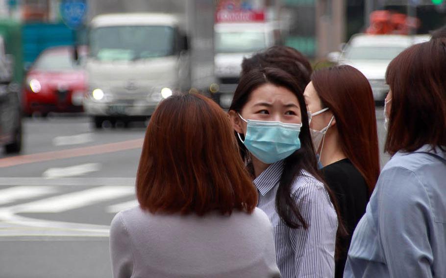 Masked pedestrians wait to cross a street in Tokyo's fashionable Omotesando district, May 22, 2020.