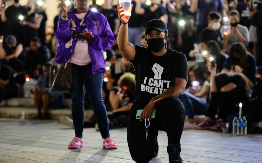 People hold up candles and cellphones during a moment of silence, which lasted nearly nine minutes, to honor George Floyd at Camp Humphreys, South Korea, Thursday, June 11, 2020.