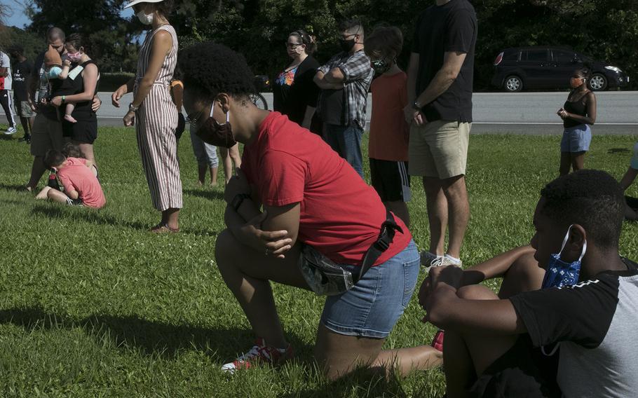 A woman takes a knee during a vigil in memory of George Floyd at Kadena Air Base, Okinawa, Saturday, June 13, 2020. Floyd, an African American, was killed last month in Minneapolis by a white police officer who has been charged with murder.