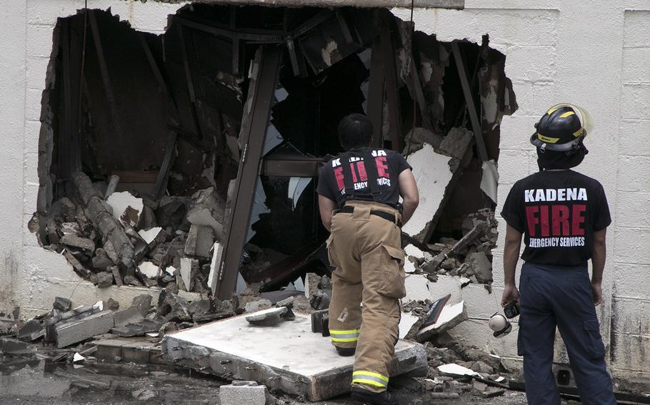 Firefighters survey damage to a hazardous materials building at Kadena Air Base, Okinawa, Tuesday, June 23, 2020, the day after it caught fire.