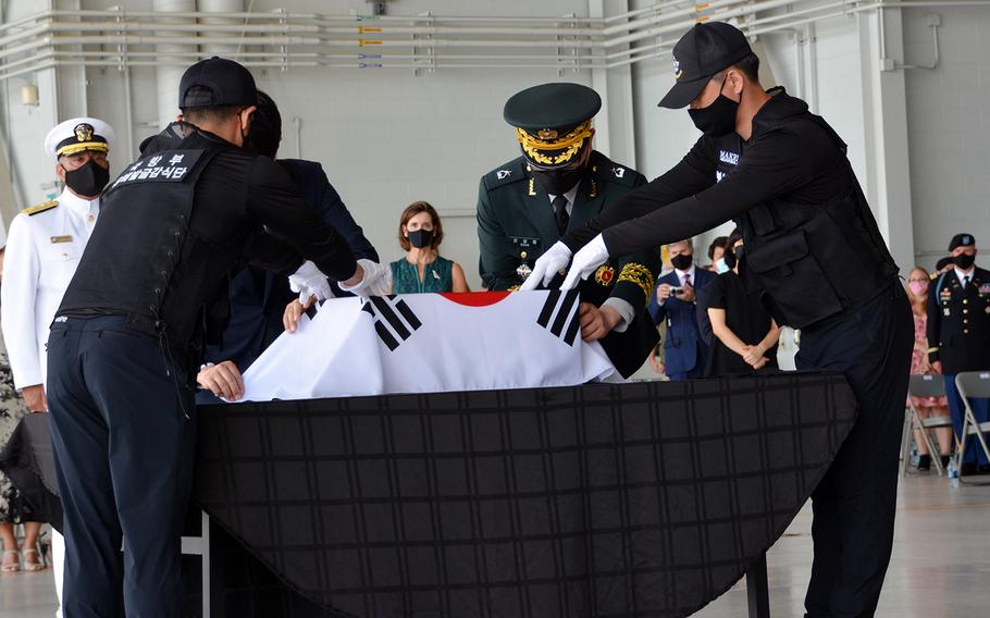 South Korean officials cloak their national flag over a box holding the remains of a countrymen who died during the Korean War during a repatriation ceremony at Joint Base Pearl Harbor-Hickam, Hawaii, Tuesday, June 23, 2020.