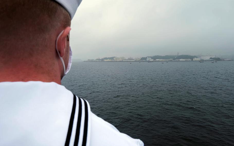 A mask-wearing sailor mans the rails as the 7th Fleet flagship USS Blue Ridge returns to Yokosuka Naval Base, Japan, Wednesday, June 24, 2020.