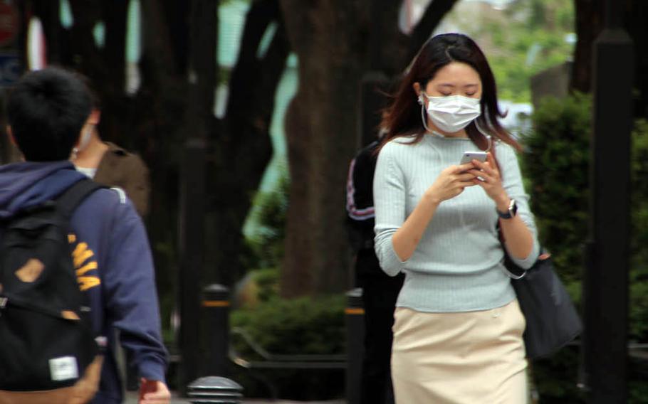 People wear masks as they stroll through the Omotesando district of central Tokyo, May 22, 2020.