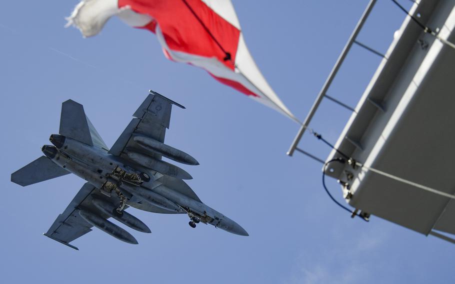 An F/A-18F Super Hornet assigned to Strike Fighter Squadron 154 flies over the aircraft carrier USS Theodore Roosevelt in the Philippine Sea, June 17, 2020.