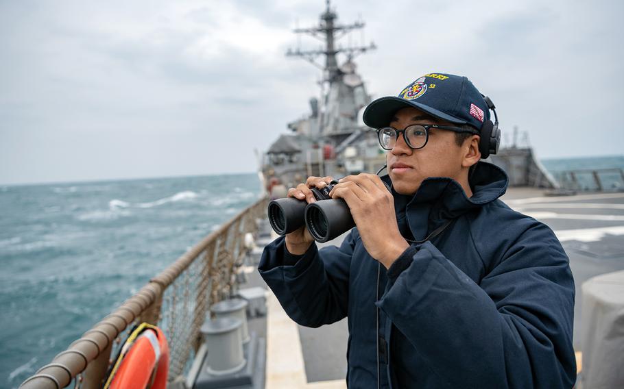 A sailor stands lookout on the flight deck of the guided-missile destroyer USS Barry as it traverses the Taiwan Strait on April 23, 2020.