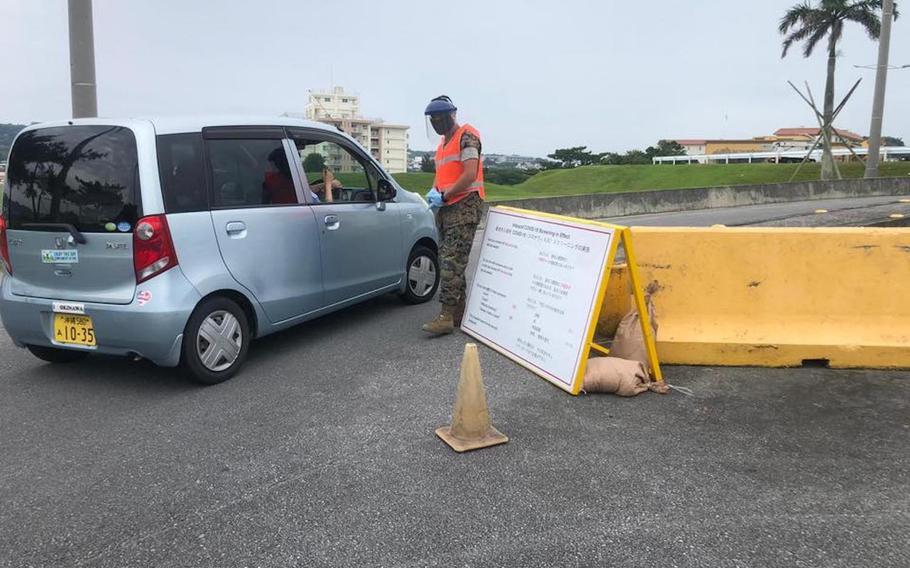 A gate guard checks a driver's temperature outside Camp Foster, Okinawa, in this image posted to the base Facebook page on May 17, 2020.