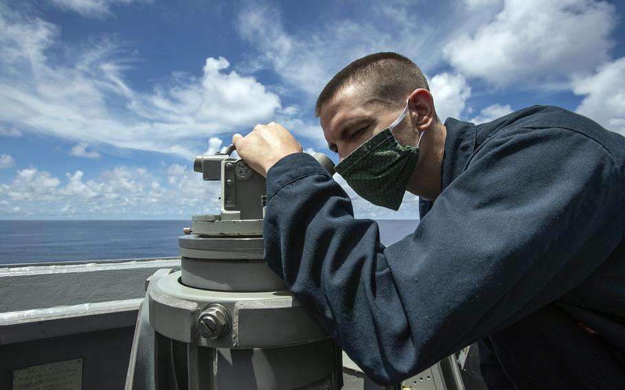 Aboard the guided-missile destroyer USS Ralph Johnson, Petty Officer 2nd Class Paul Vance scans the horizon near the Spratly Islands in the South China Sea, July 14, 2020.