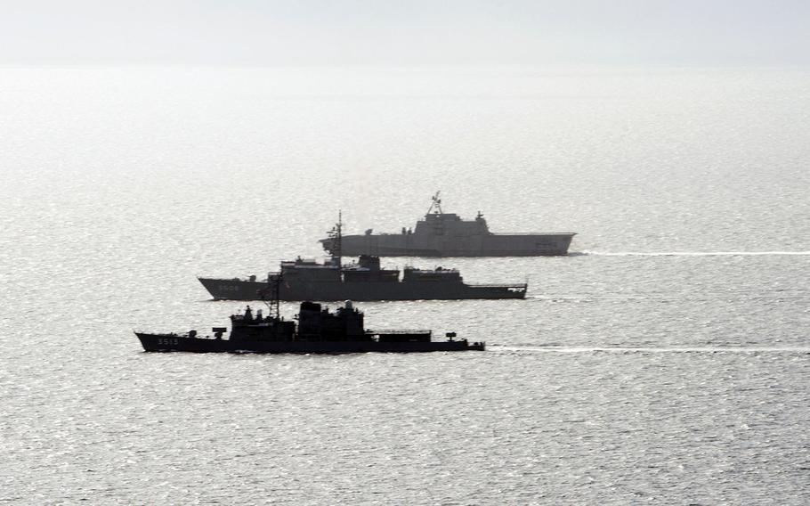 The Japan Maritime Self-Defense Force ships JS Kashima, bottom, and JS Shimayuki, center, train alongside the littoral combat ship USS Gabrielle Giffords in the South China Sea, June 23, 2020.