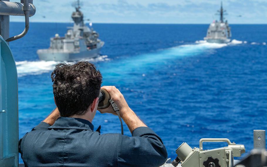 Ens. David Falloure of the guided-missile cruiser USS Antietam uses a rangefinder to determine the distance to Australia's HMAS Stuart, left, and Japan's JS Teruzuki in the South China Sea, July 21, 2020.