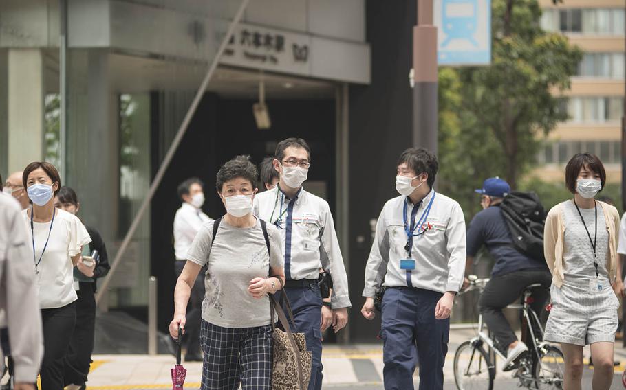 Pedestrians cross a street outside Roppongi Station in central Tokyo, July 21, 2020.