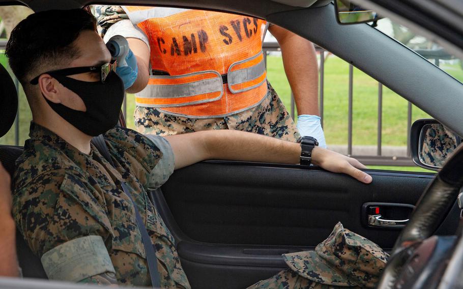 A Marine's temperature is taken before driving onto Camp Foster, Okinawa, July 29, 2020.