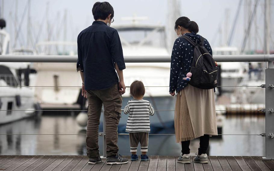 A family wears masks while checking out boats near Kanazawa-Hakkei Station in Yokohama, Japan, July 16, 2020.