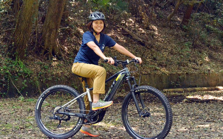 Tama Hills Recreation Center employee Yuki Ono poses on an electric mountain bike on one of the center's trails in western Tokyo, Thursday, Aug. 6, 2020.