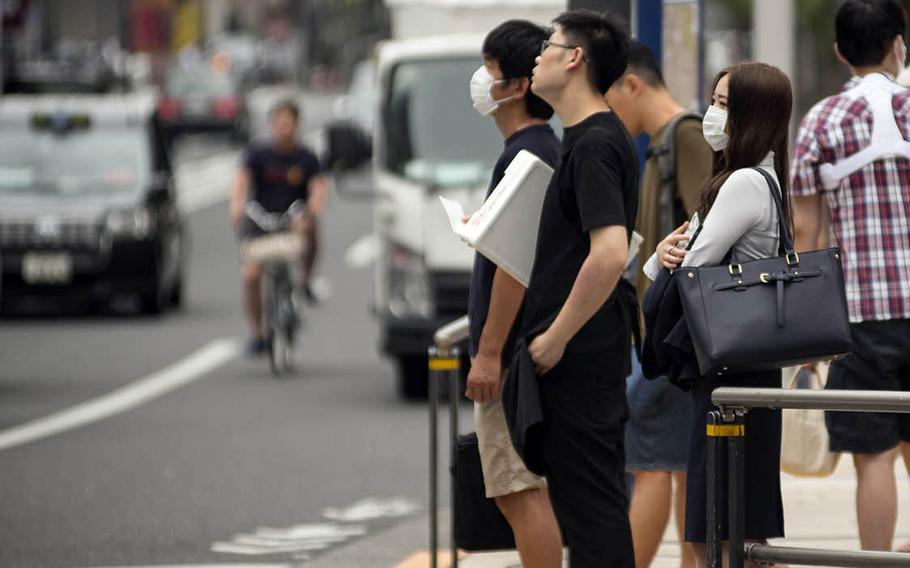 Pedestrians wait to cross a busy street in the Roppongi district of central Tokyo, July 21, 2020.