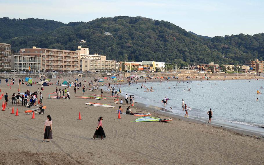 People, some wearing masks to protect against the coronavirus, hang out at a beach in Hayama, Japan, Thursday, Aug. 13, 2020.
