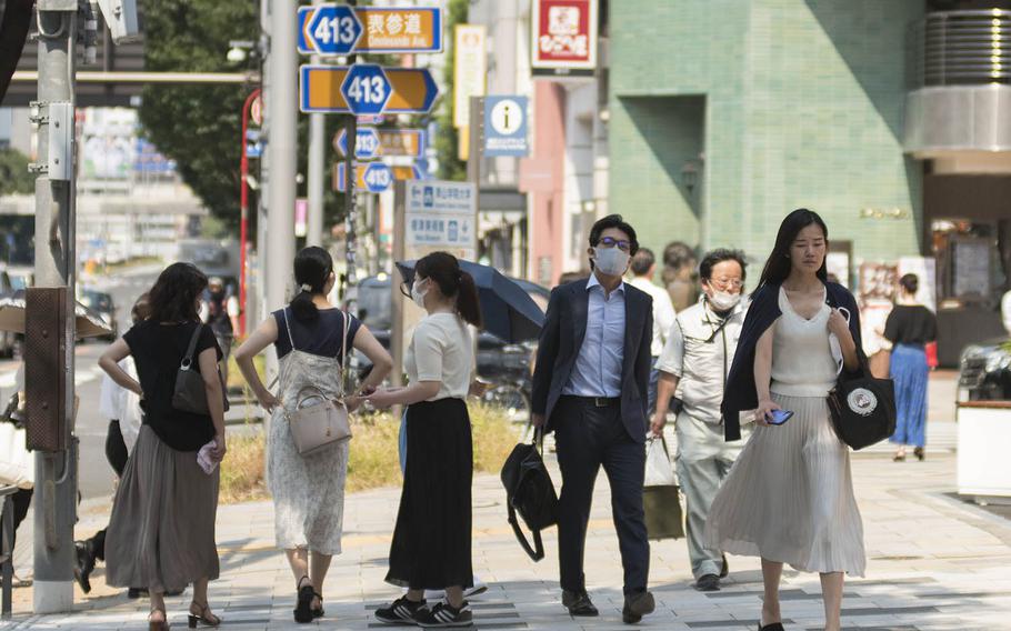 People stroll through the Omotesando district of central Tokyo, Aug. 14, 2020.