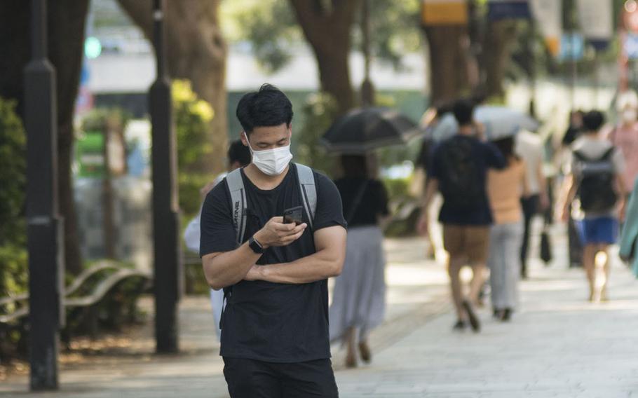 A man stops to check is smartphone in the Omotesando area of central Tokyo, Aug. 14, 2020. 