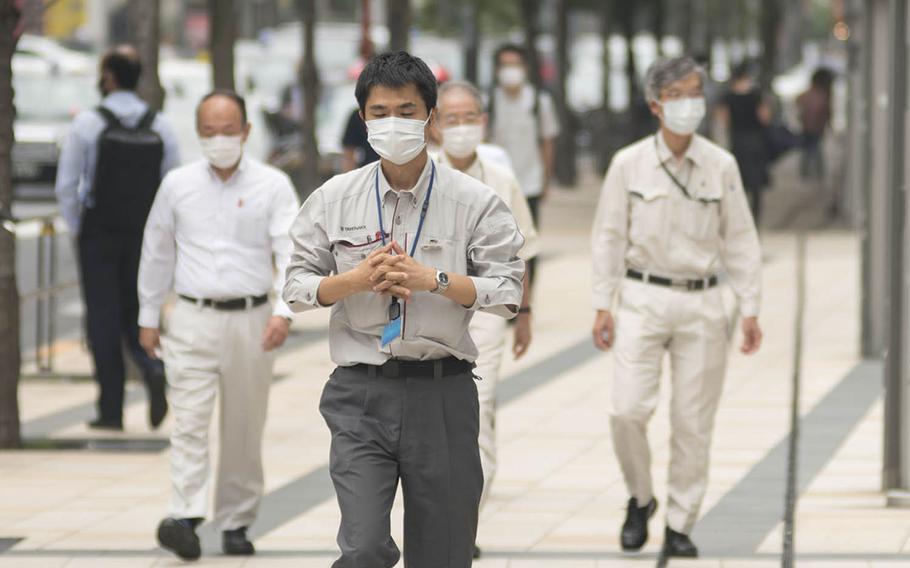 Mask-wearing pedestrians walk down a street on a recent afternoon in the Roppongi district of central Tokyo. 