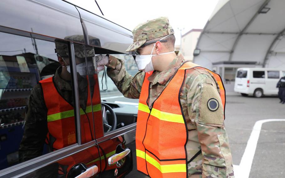 A soldier takes the temperature of a driver at Camp Zama, Japan, March 31, 2020.