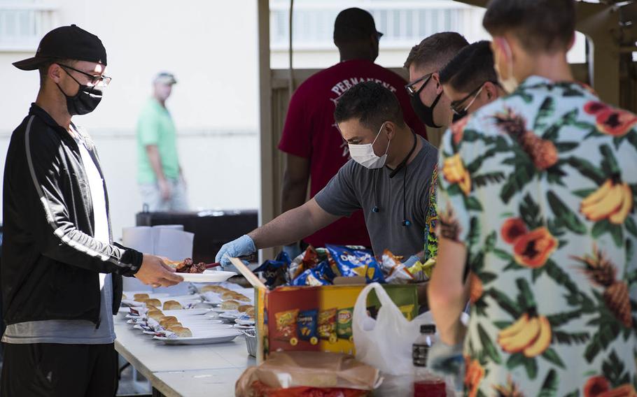 Volunteers dish out some comfort food to a quarantined service member during a barbecue at Yokota Air Base, Japan, Friday, Sept. 4, 2020. 