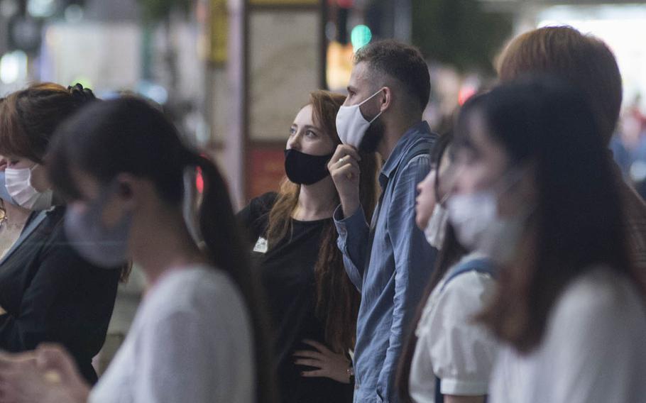 People wait to cross a street in the Kabukicho entertainment district in central Tokyo, Sept. 2, 2020.