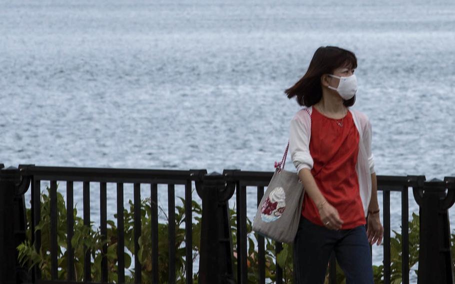 A woman wears a mask to protect against the coronavirus while taking a walk near Yokosuka Naval Base, Japan, Aug. 27, 2020.