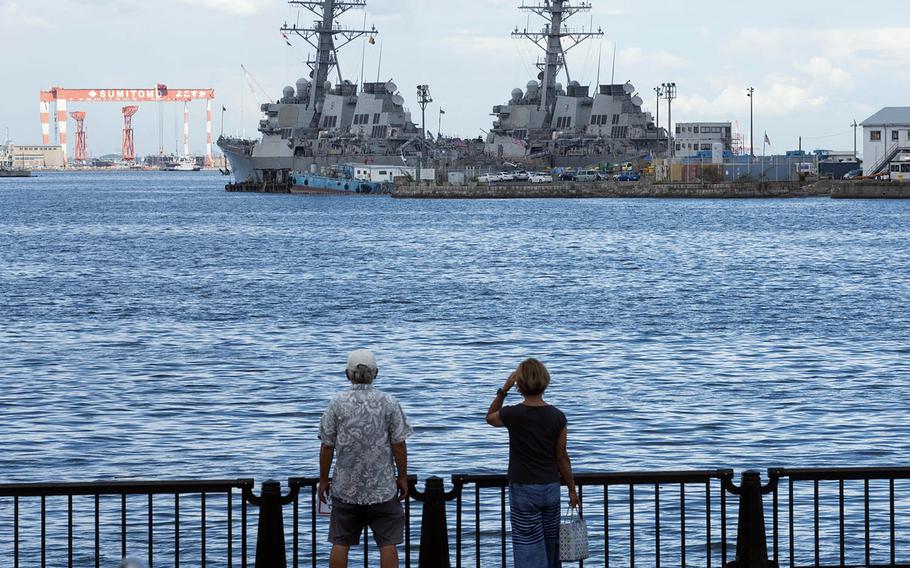 People check out a pair of warships docked at Yokosuka Naval Base, Japan, Aug. 27, 2020.