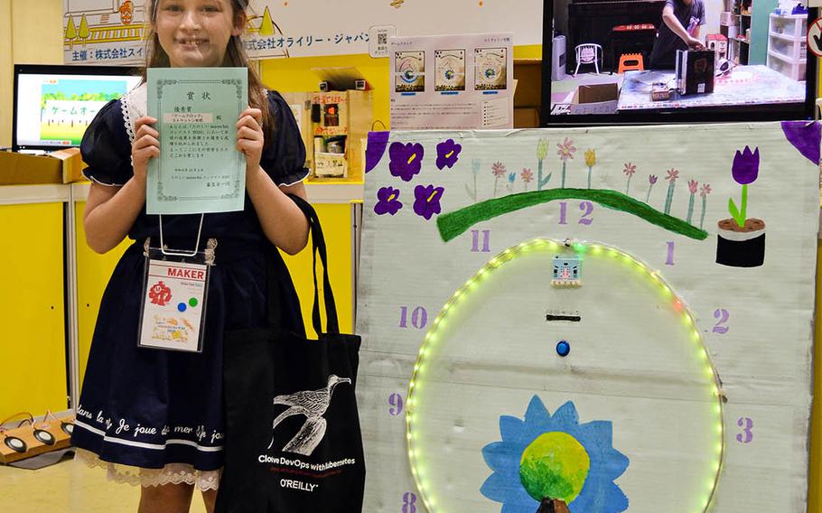 Alice Stratton, a fourth-grader at Daihachi Elementary School near Yokota Air Base, Japan, poses beside her invention, an LED game clock, during Maker Faire 2020 in Tokyo, Saturday, Oct. 3, 2020.