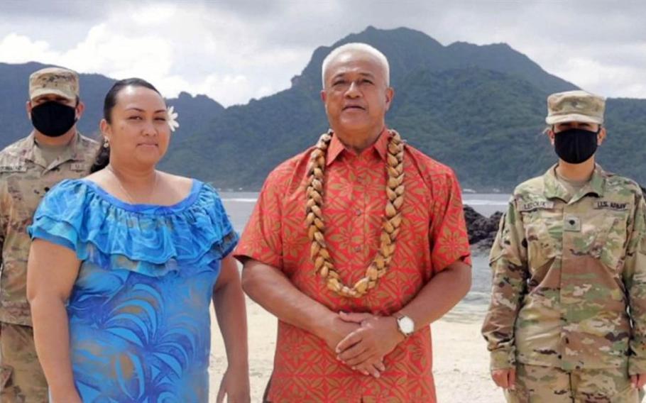 In this image from video, two soldiers stand at attention as Aliitama Sotoa, chairman of the American Samoa Democratic Party, in orange, casts the territory's 11 votes for Joe Biden in a brief segment of the Democratic National Convention on Aug. 8, 2020.