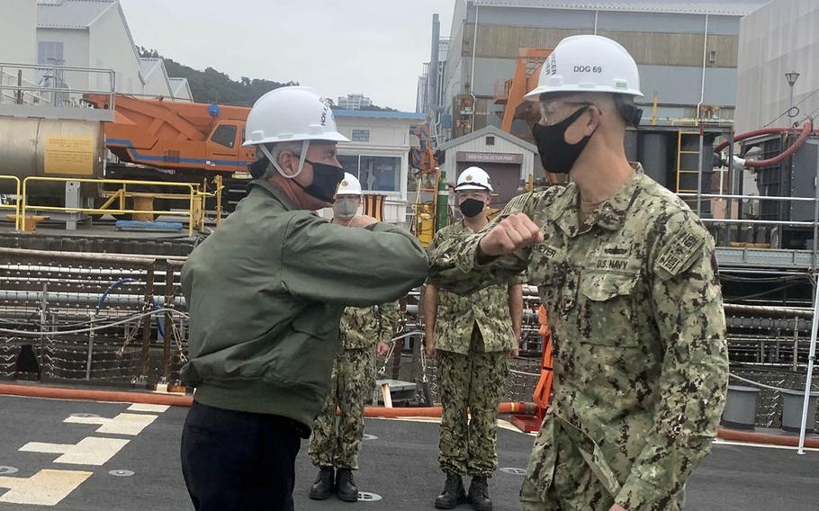 Navy Secretary Kenneth Braithwaite, left, greets the commanding officer of the USS Milius, Cmdr. Rob Niemeyer, aboard the guided-missile destroyer in dry dock at Yokosuka Naval Base, Japan, Thursday, Oct. 15, 2020.