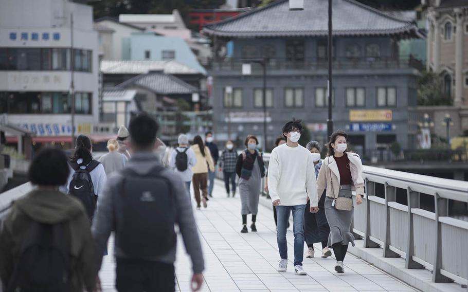 Tourists wear masks as they cross a bridge near Enoshima, Japan, Friday, Oct. 30, 2020.