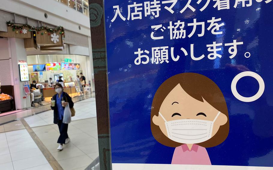 A sign reminds shoppers to wear a mask inside a mall in western Tokyo, Sunday, Nov. 8, 2020.