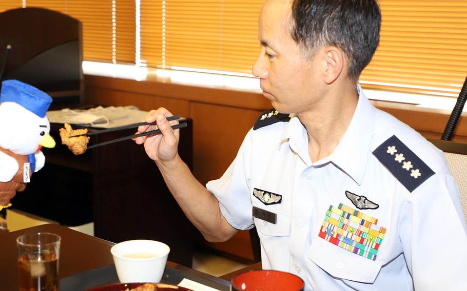 Gen. Shunji Izutsu, chief of staff for the Japan Air Self-Defense Force, pretends to feed fried chicken to the service's mascot in this undated photo.
