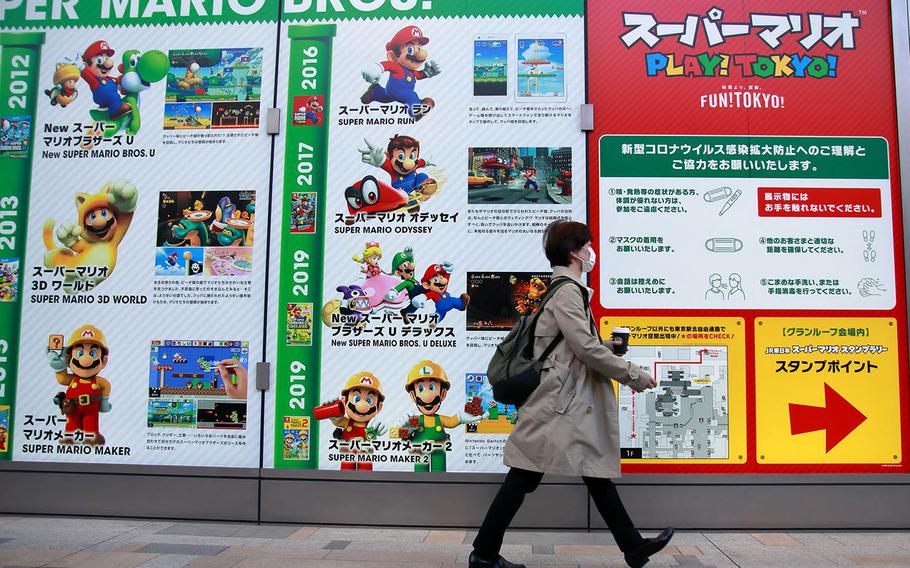 A woman walks past a Tokyo Station exhibit celebrating the 35th anniversary of the Super Mario Bros. video game franchise, Nov. 4, 2020.