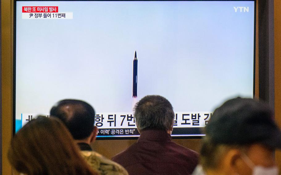 People sit near a television screen showing a news broadcast with file footage of a North Korean missile test, at a railway station in Seoul on Sunday, Oct. 9, 2022. 