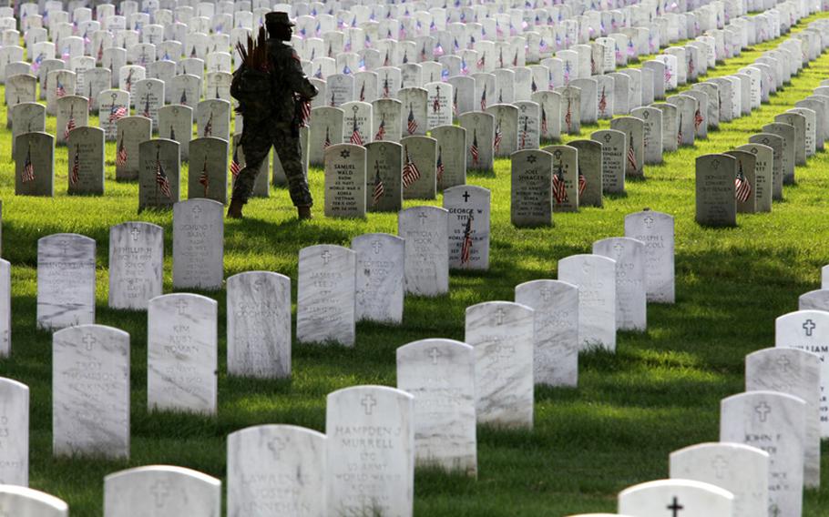 Army 1st Sgt. Shelly Jenkins, with the 3rd U.S. Infantry Regiment known as The Old Guard, places flags on the graves at Arlington National Cemetery in preparation for Memorial Day 2010.