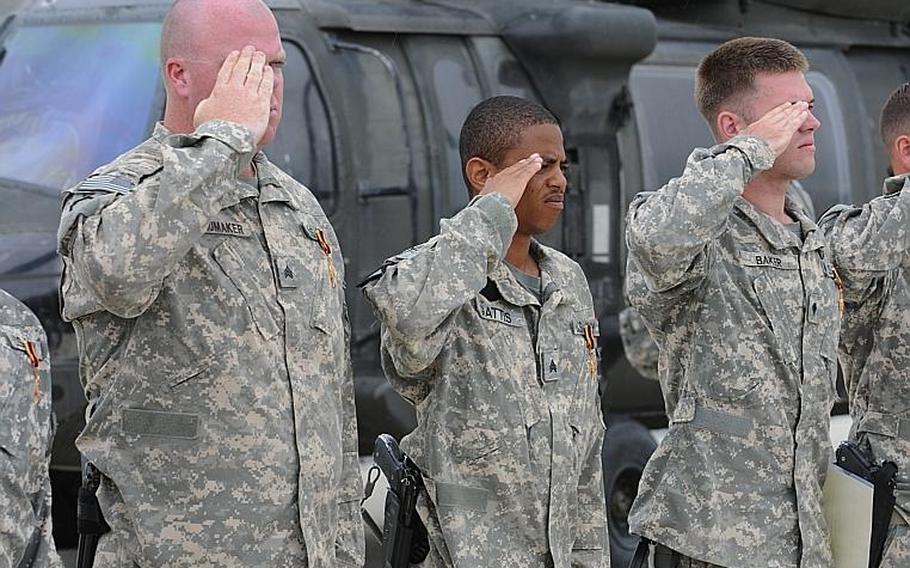 Left to right, U.S. Army Sgt. Steven Schumaker, Sgt. Antonio Gattis and Spc. Matthew Baker with the 5th Battalion, 158th Aviation Regiment salute during the national anthem on May 12 after receiving Germany's Gold Cross in Kunduz, Afghanistan.